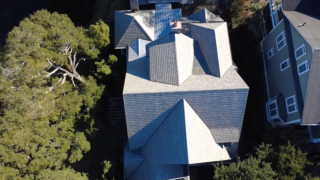 Aerial view of a house with a complex shingle roof.