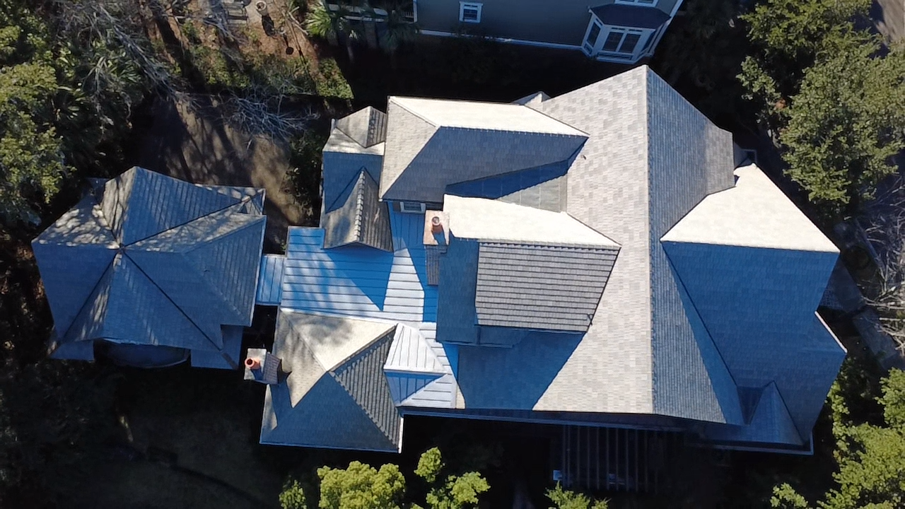 Aerial view of a house with a complex shingle roof.
